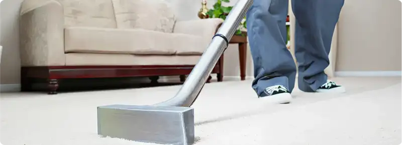 Carpet cleaning technician using a hot-water extraction wand on a light-colored carpet in a living room, South Bend, IN.