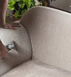 Professional upholstery cleaner deep-cleaning a fabric sofa with a handheld extraction tool and hose South Bend, IN.