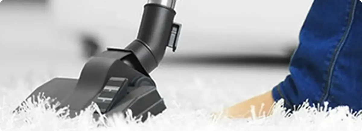 Close-up of a professional vacuuming a white carpet in Edwardsburg.